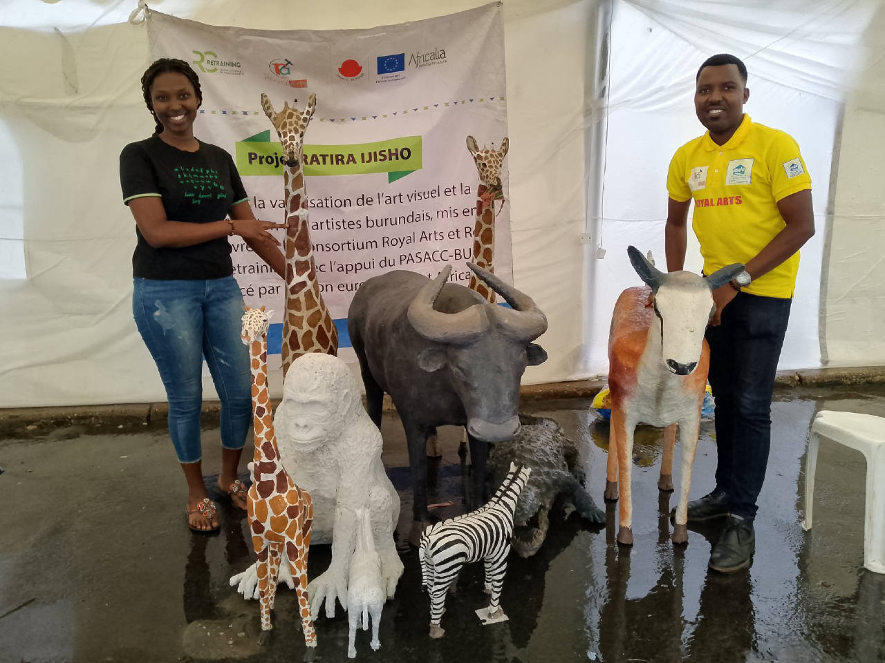 Deux personnes présentent des sculptures d’animaux sur un stand Royal Arts.